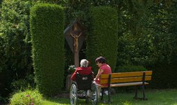 Senioren sitzen vor Gartenkreuz | © © Photographien Thomas Klinger, www.atelierklinger.de